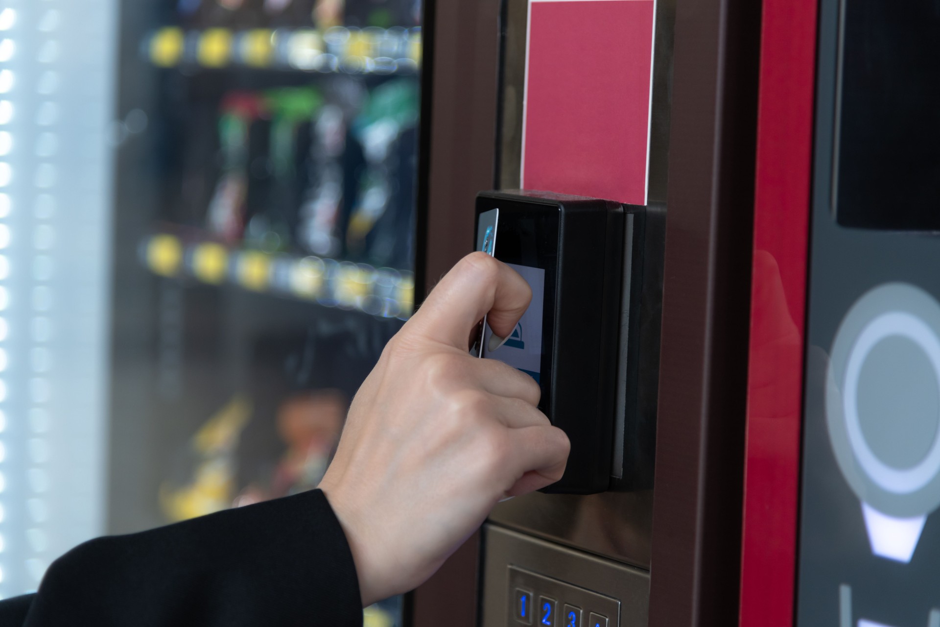 Woman buying snack from vending machine in busy location